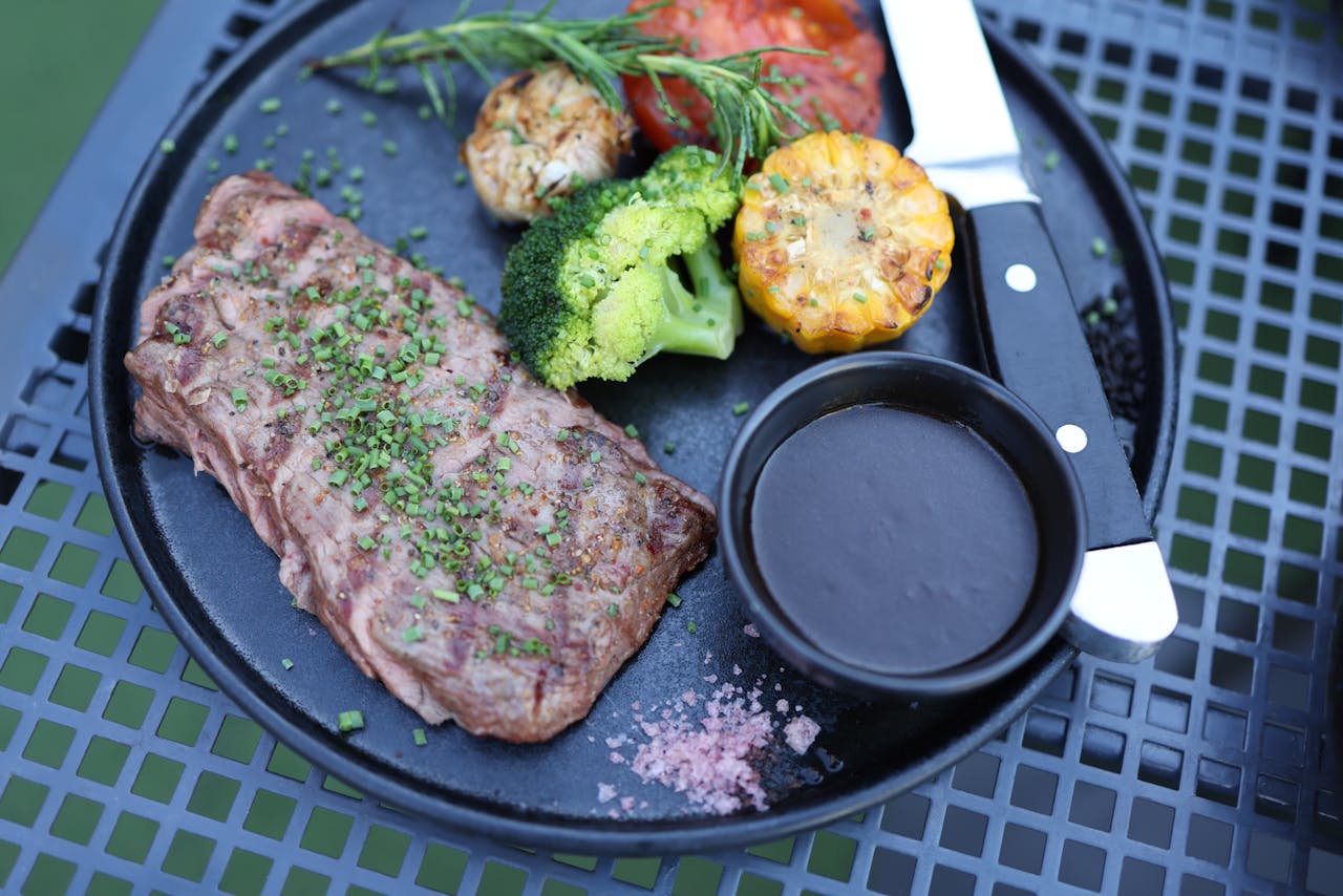 Delicious steak served with vegetables and dipping sauce on a stylish plate.